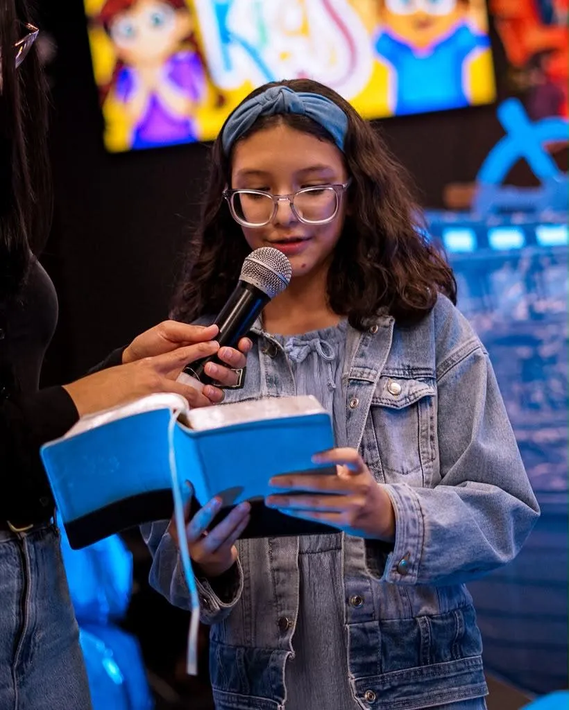 Una niña lee la Biblia frente a la iglesia