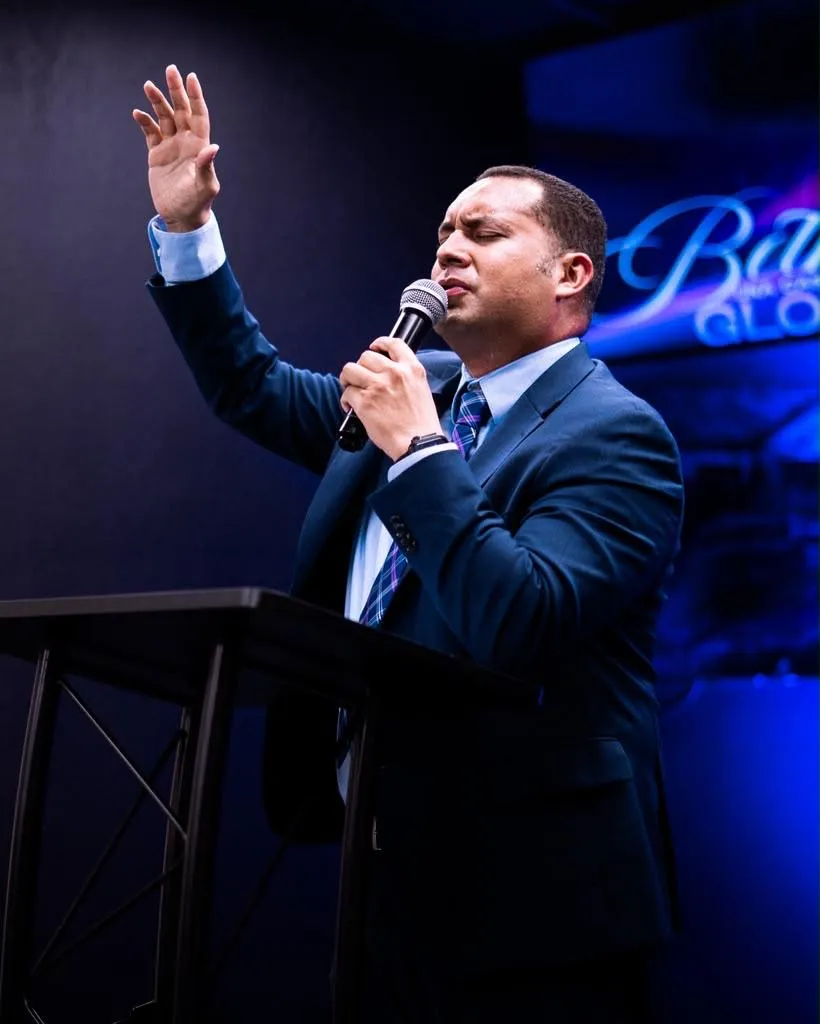 El pastor Oscar Tovar predicando con la mano levantada