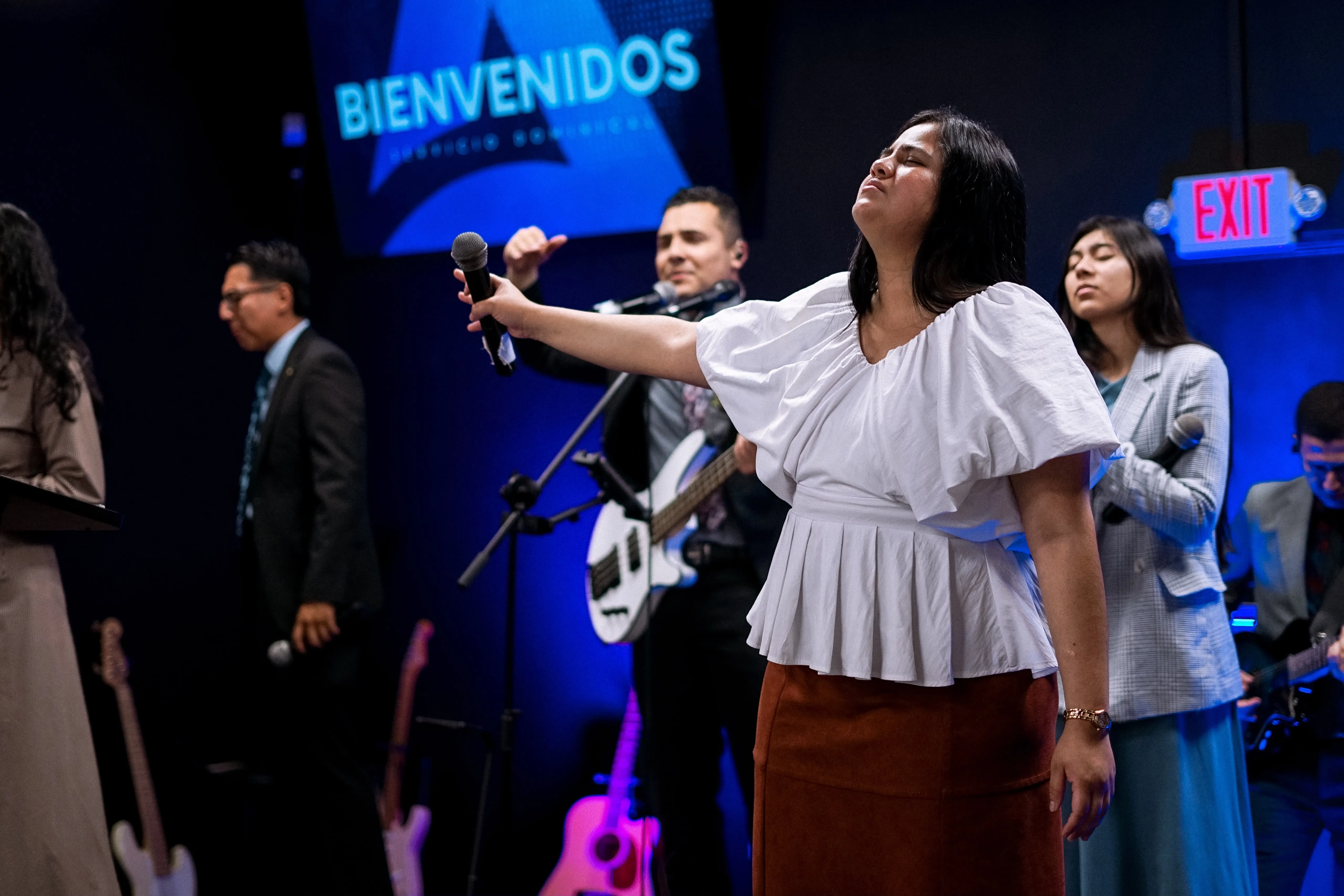 Una mujer adora con los brazos abiertos durante un servicio de Adorar Church