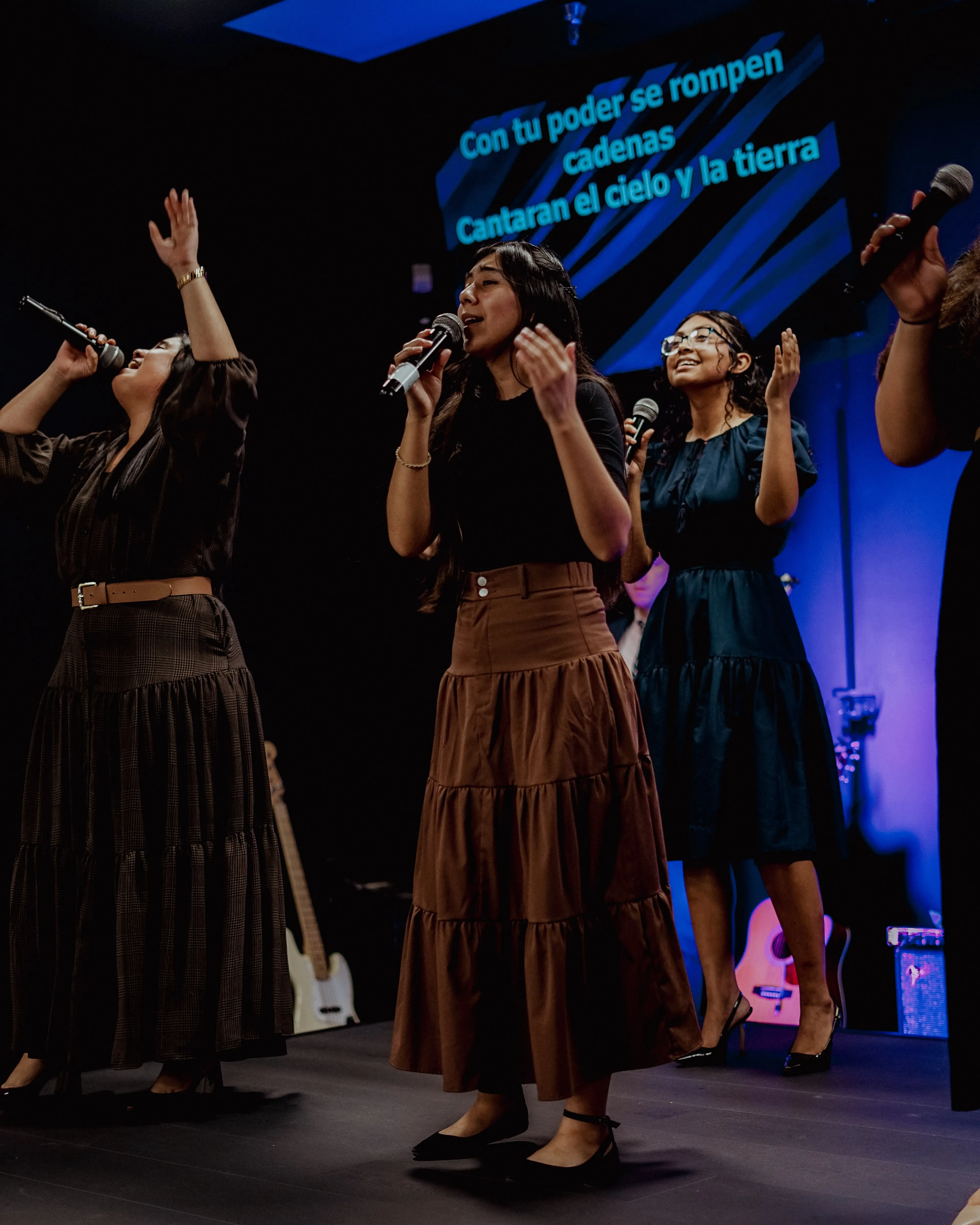 Tres mujeres dirigen la adoración en el escenario
