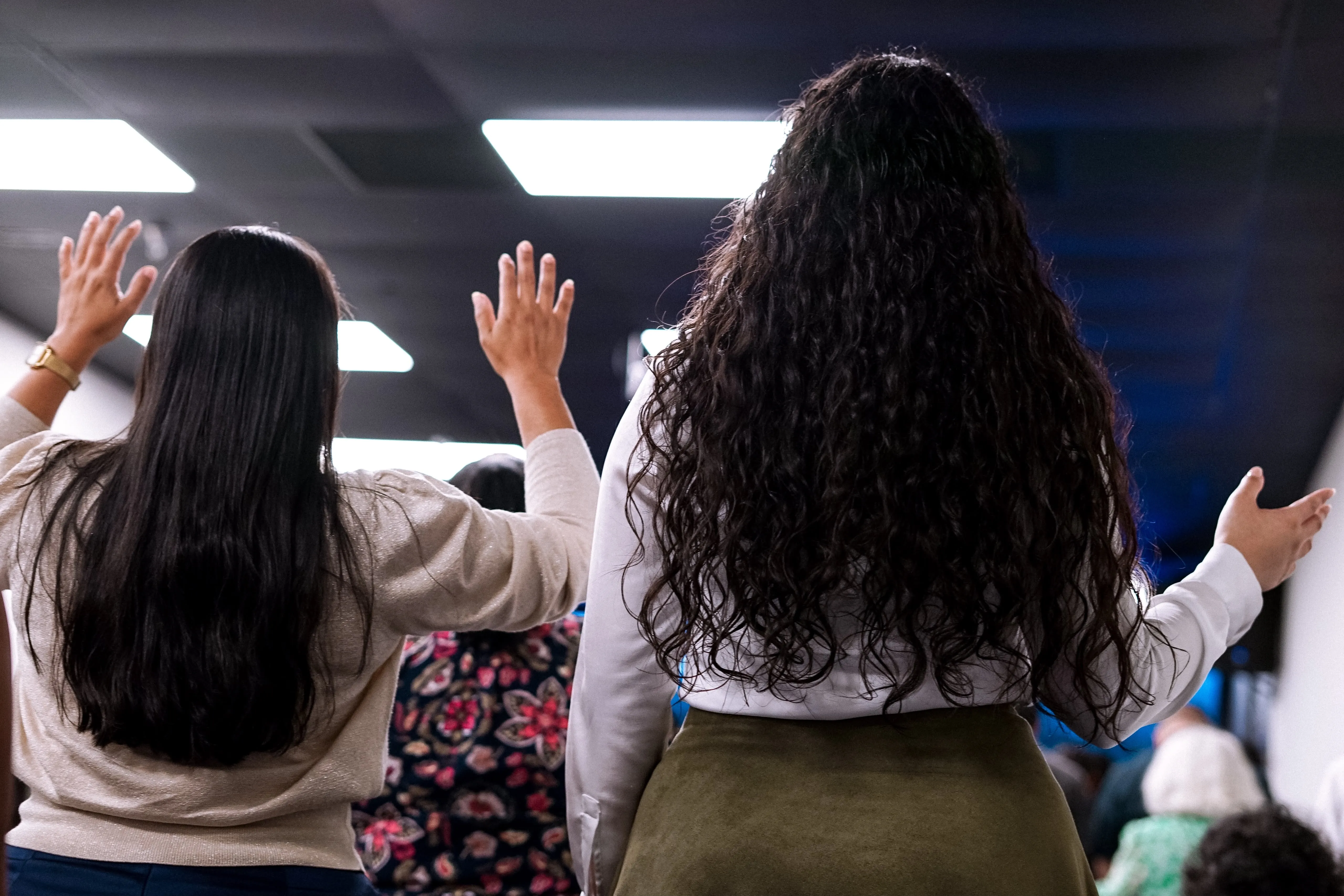 Dos mujeres adoran con las manos levantadas durante el servicio